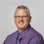 Randy Sondrol wearing a purple dress shirt and purple tie.